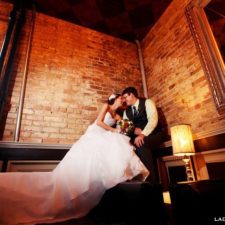 Image of bride and groom backroom kiss in front of the exposed brick walls in Northwest Indiana's historic wedding venue and events center