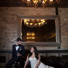 Image of bride and groom staring at each other on a leather couch in the back lounge of a Northwest Indiana historic banquet hall